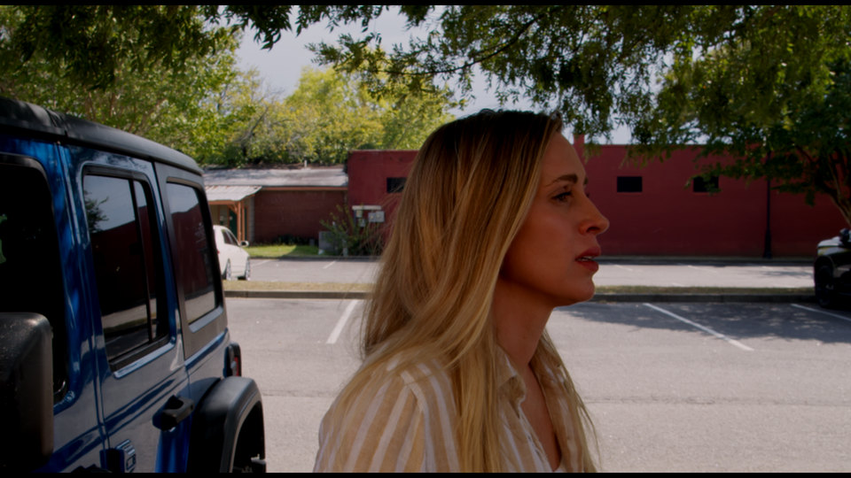 Her friend by the blue Jeep in the parking lot