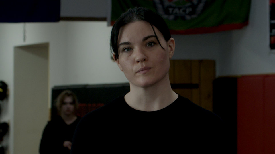 Emma stands in the gym, jaw set